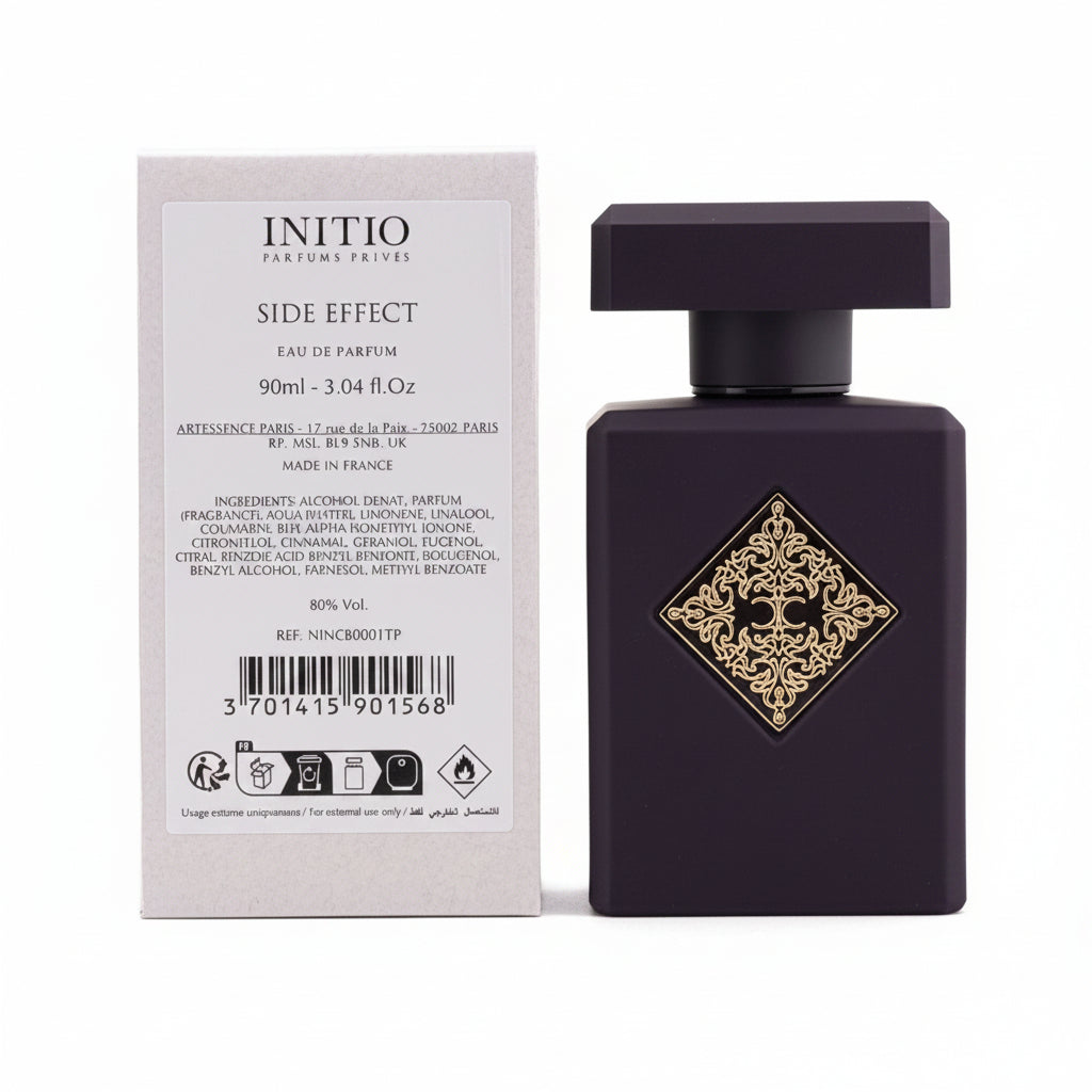 Black perfume bottle with decorative label next to its packaging on a light gray background