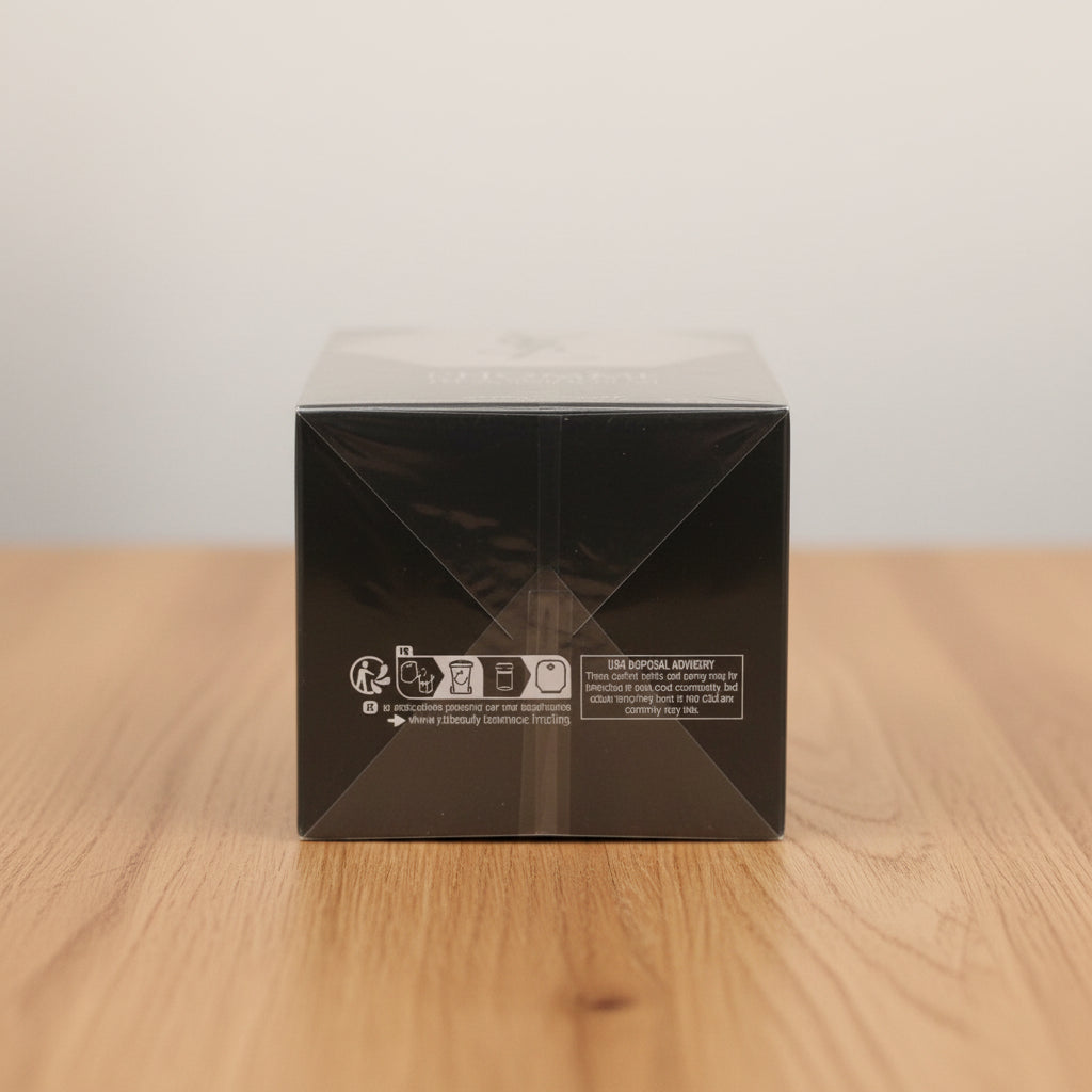 A black rectangular product box wrapped in clear plastic, featuring a silver geometric logo and the text 'L'HOMME' on the top panel, photographed against a light gray background.
