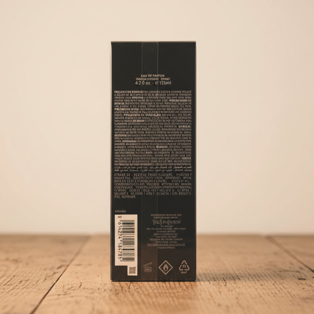 The back of a tall, dark gray rectangular product box wrapped in protective plastic, showing white text, a barcode, and recycling symbols, set against a neutral light gray background.