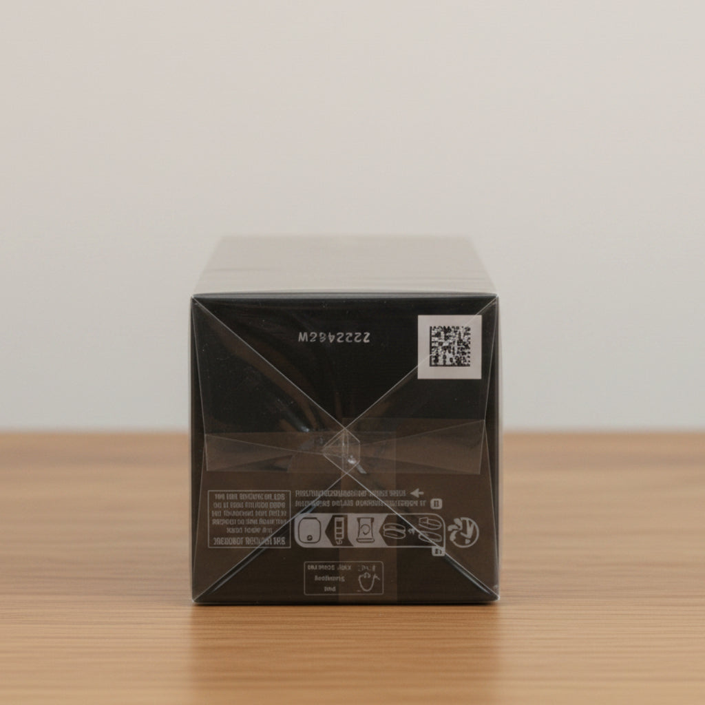 A black rectangular product box wrapped in protective plastic, photographed against a seamless light gray studio background.