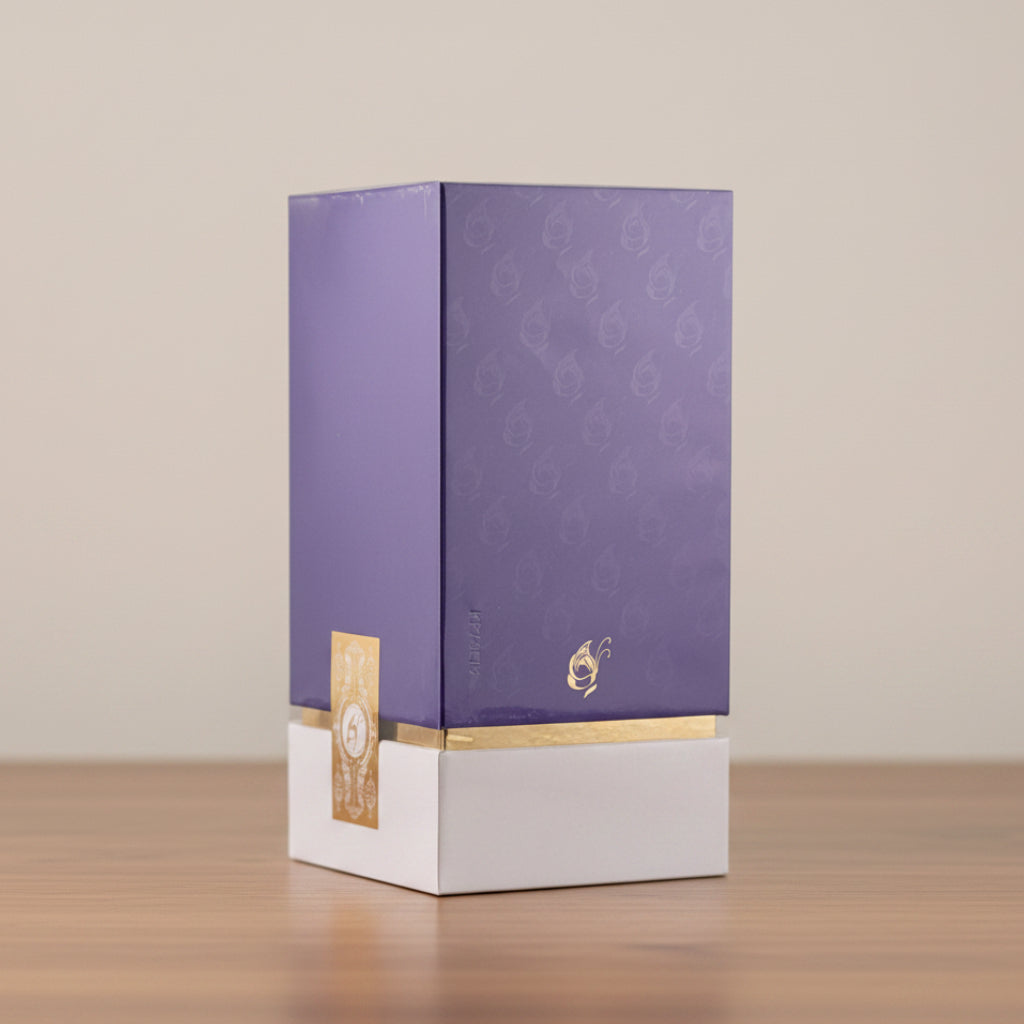 A purple rectangular product box with a white base, featuring subtle gold foil patterns, a small gold emblem, and a gold label on the side, photographed against a plain light background.