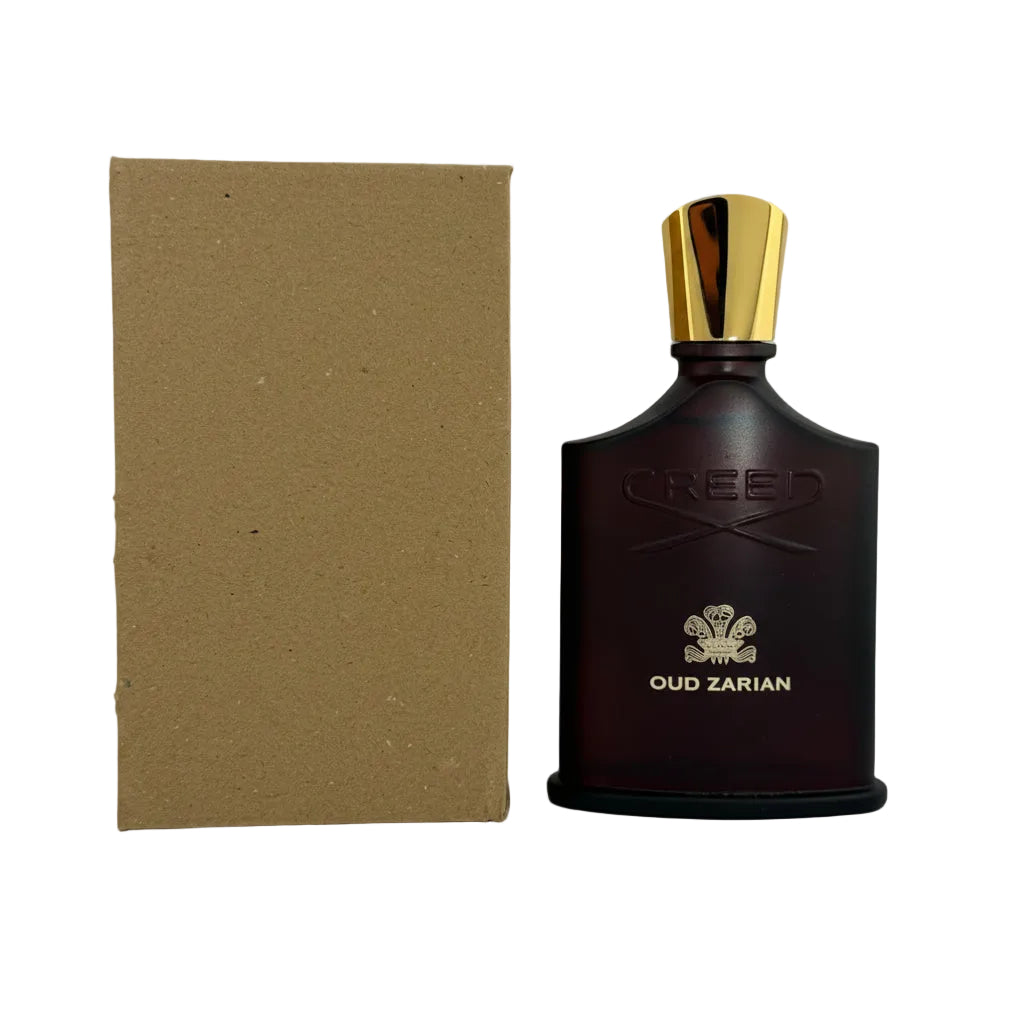 Creed Oud Zarian perfume bottle in a dark amber-brown glass with a metallic gold cap, standing next to its brown cardboard box on a light gray background.