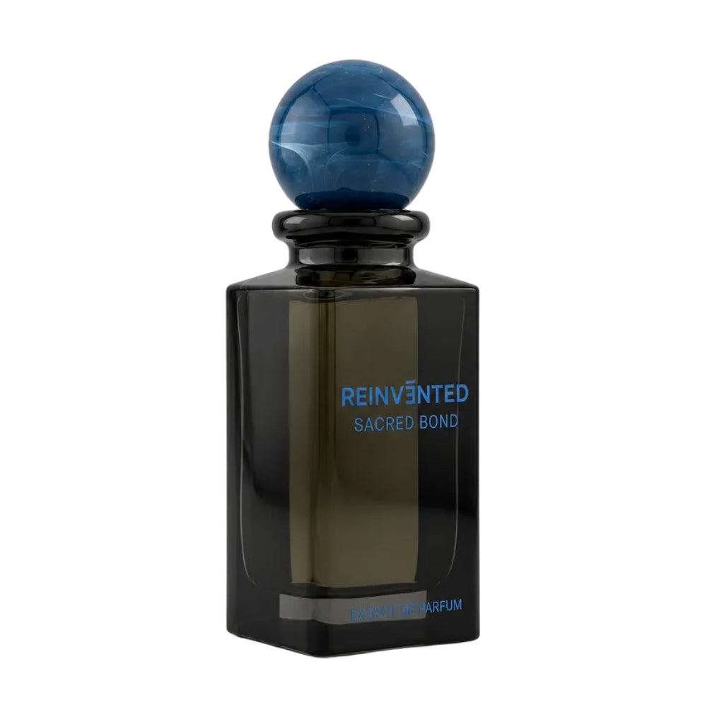A dark amber glass perfume bottle with a spherical blue marbled stopper, labeled 'REINVENTED SACRED BOND' on a neutral light gray background.