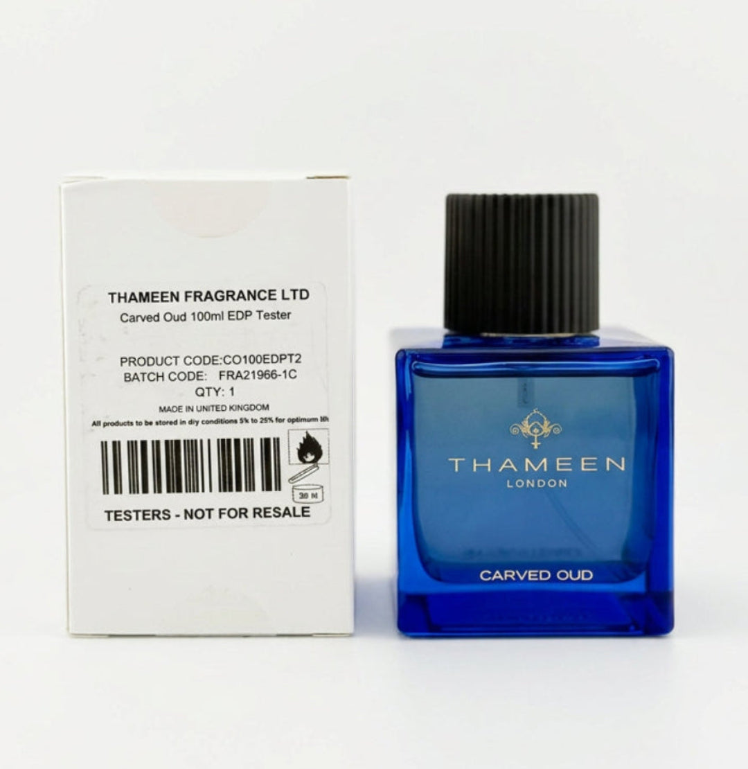 A bottle of Thameen Carved Oud fragrance next to its white cardboard packaging box, set against a plain light gray background.