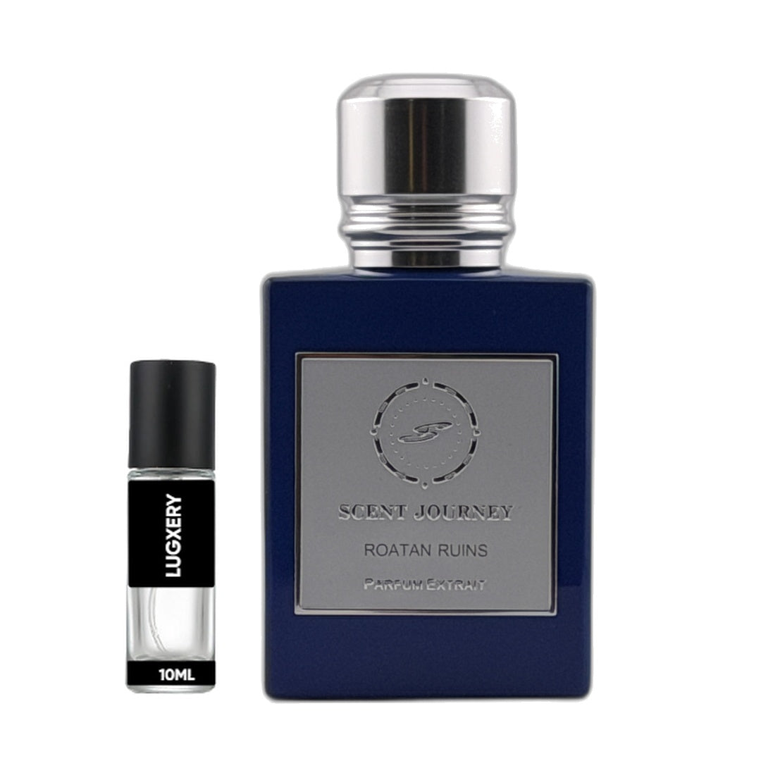 A 10ml travel perfume sample vial next to its 100ml original bottle. The original bottle is dark blue with a silver metallic cap and a silver label reading 'SCENT JOURNEY ROATAN RUINS'.
