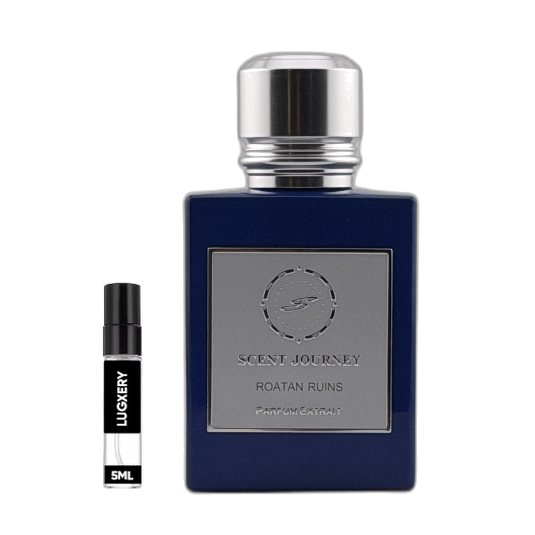 A dark blue rectangular perfume bottle with a silver cap and a silver front label reading 'SCENT JOURNEY ROATAN RUINS PARFUM EXTRAIT', shown next to a small black and white sample spray vial labeled 'LUGERY 5ML' on a white background.